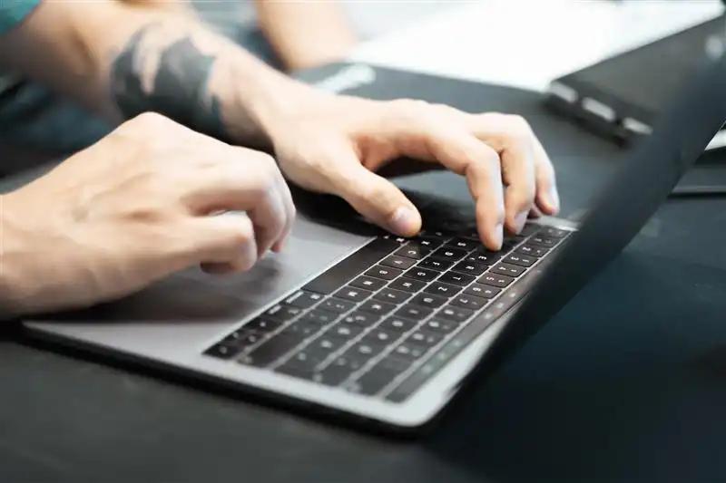 Una persona lavora su un laptop, si vedono solo le mani che utilizzano il touchpad e digitano sulla tastiera