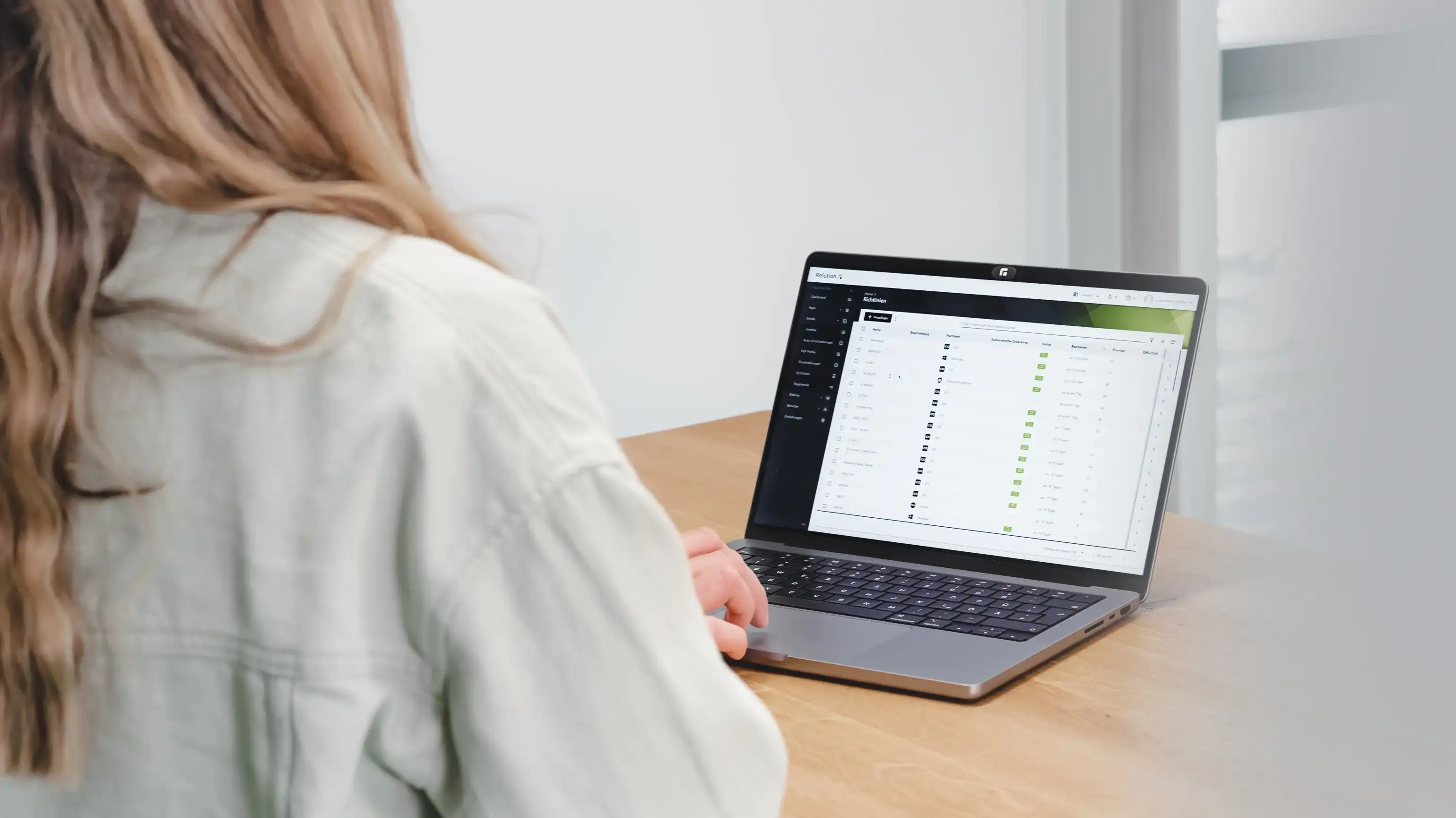Una persona está sentada de espaldas al espectador, frente a un MacBook que muestra el portal de Relution