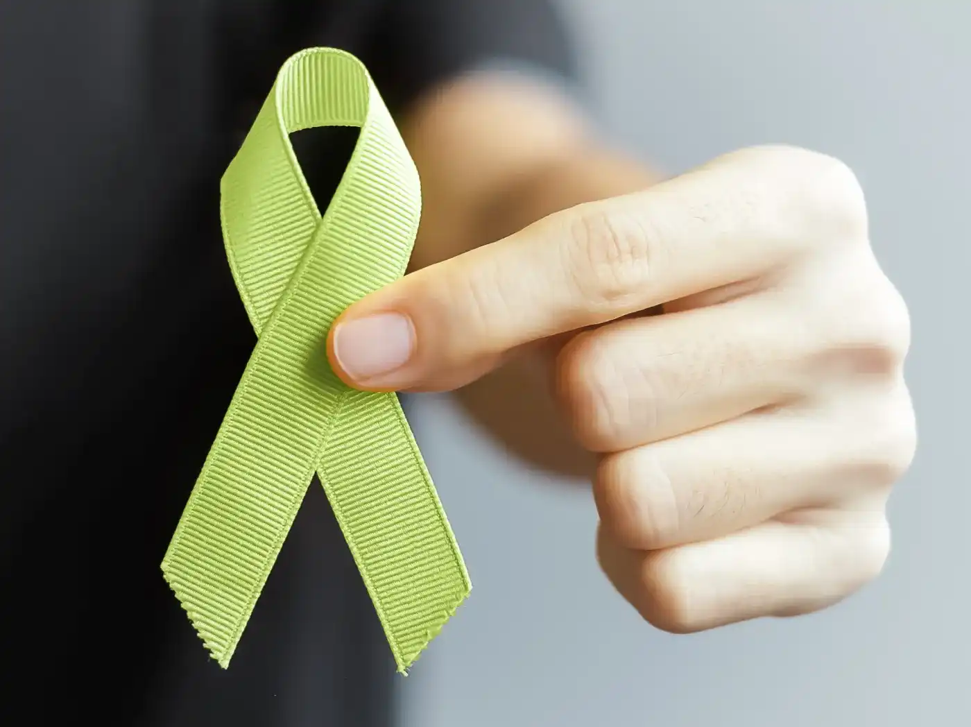 Se sostiene un lazo verde frente a la cámara, llevado en la mano por una persona