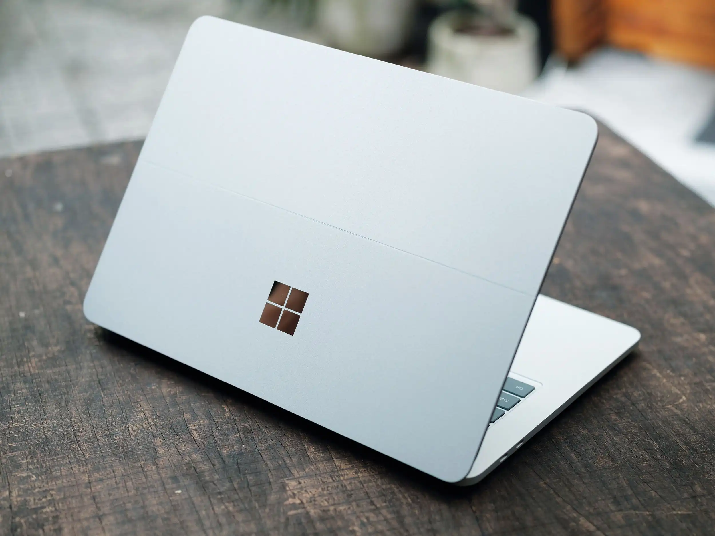 Ein Laptop mit einem Windows-Logo steht auf einem dunklen Holztisch