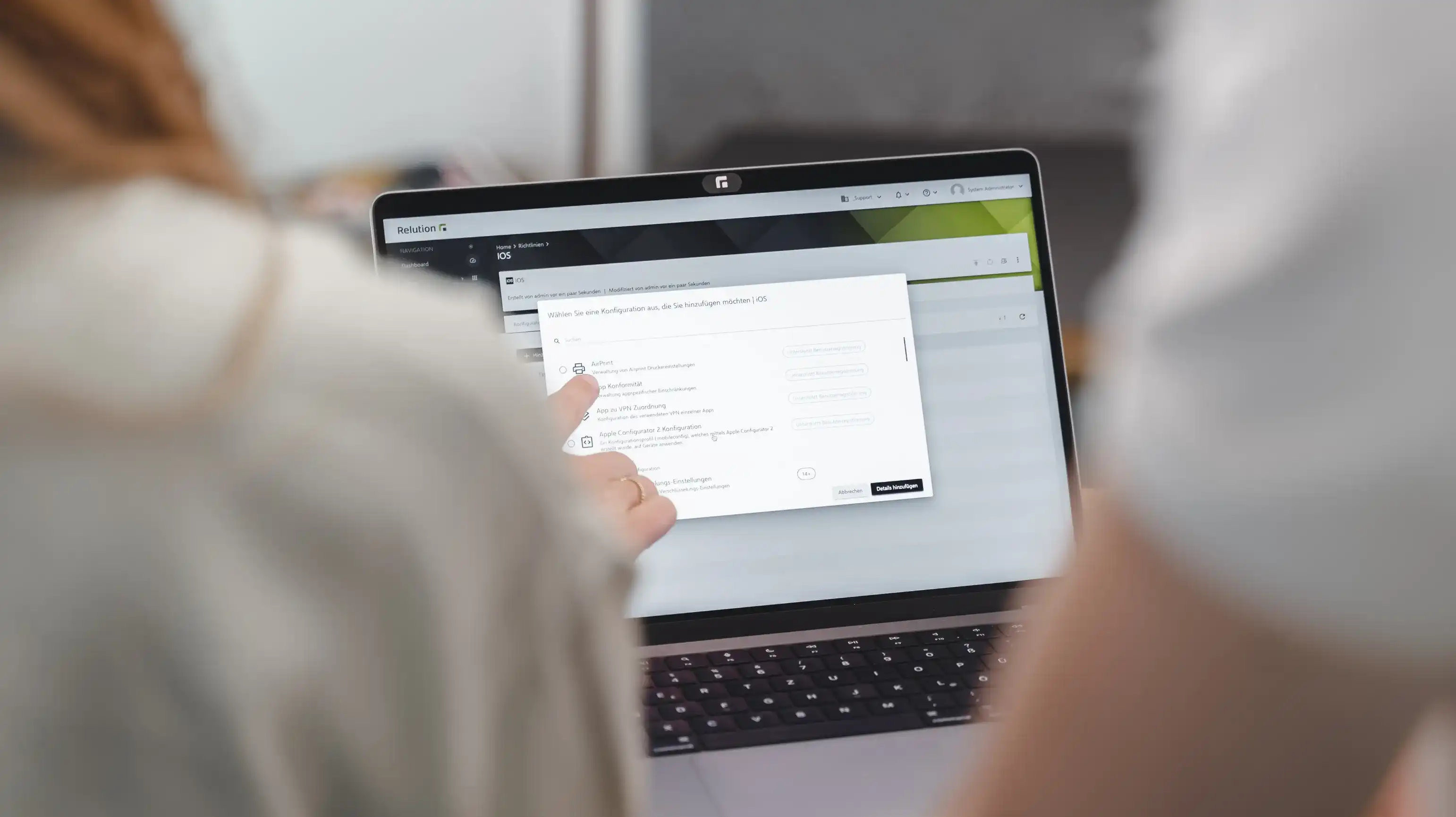 Una persona indica uno schermo di laptop che mostra una finestra nell'app Relution per aggiungere una configurazione