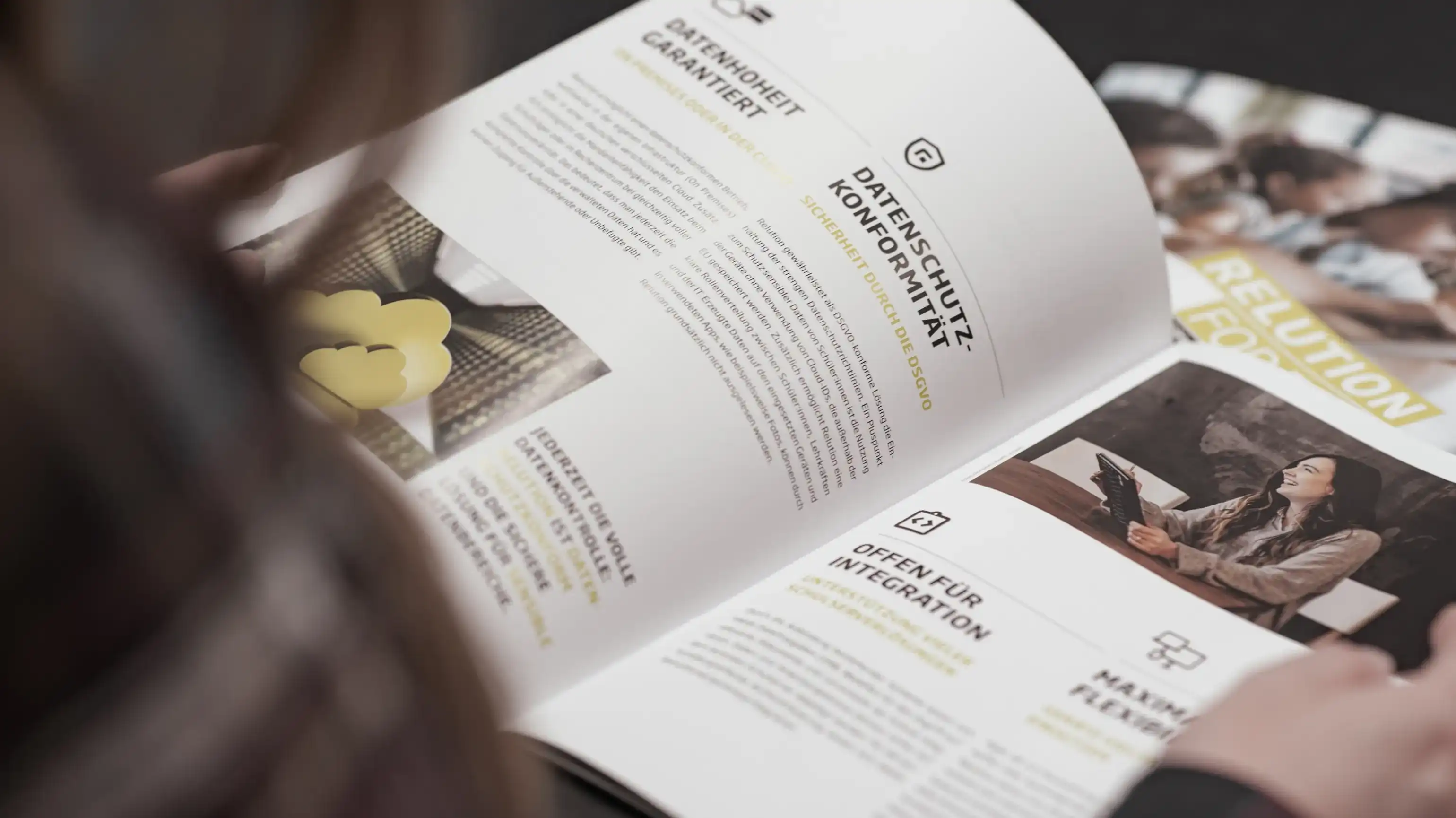 A person is sitting with their back to the camera and flipping through a brochure featuring information about Relution