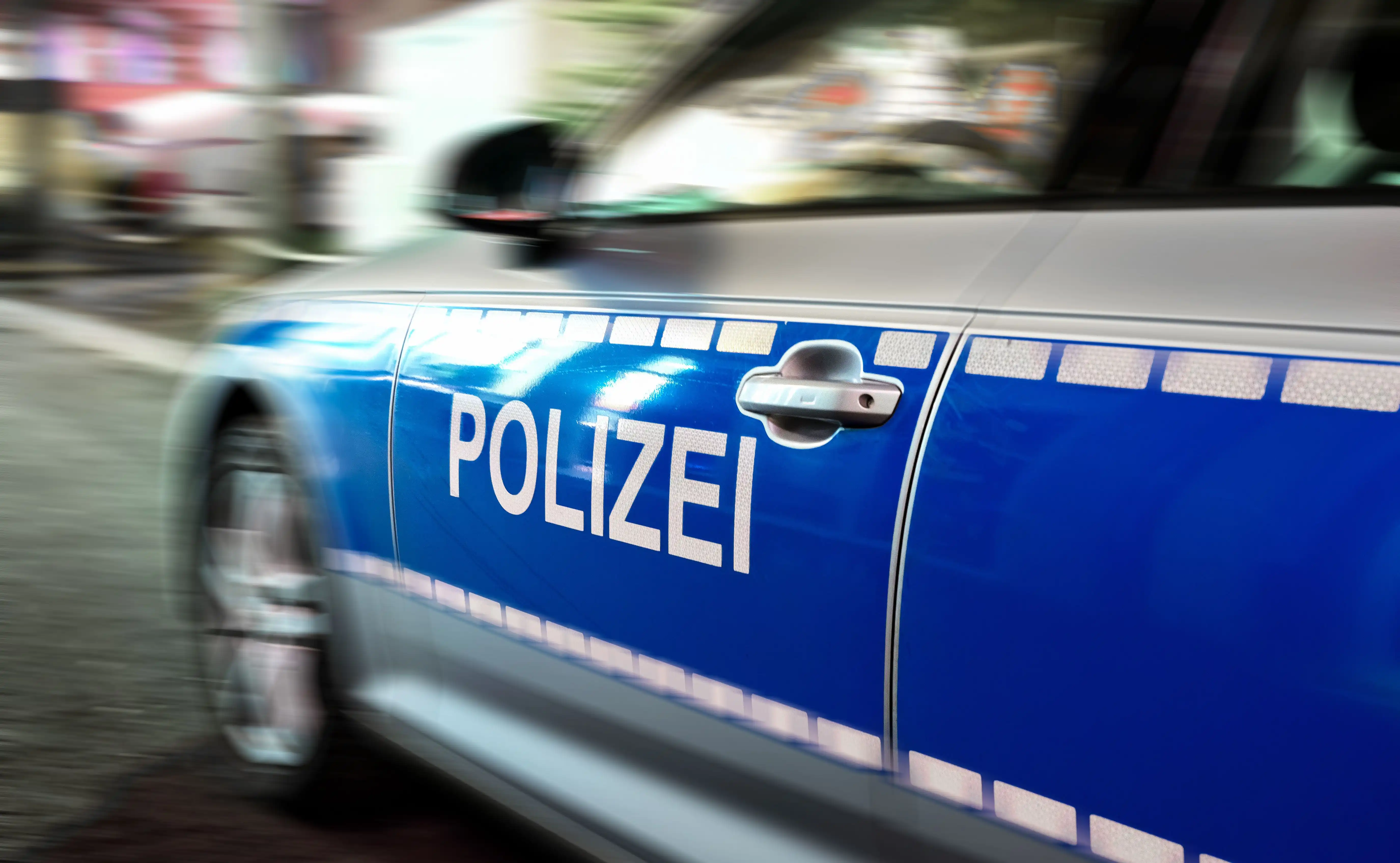 Seitenansicht eines fahrenden Polizeiwagens mit der Aufschrift "POLIZEI", mit Bewegungsunschärfe.