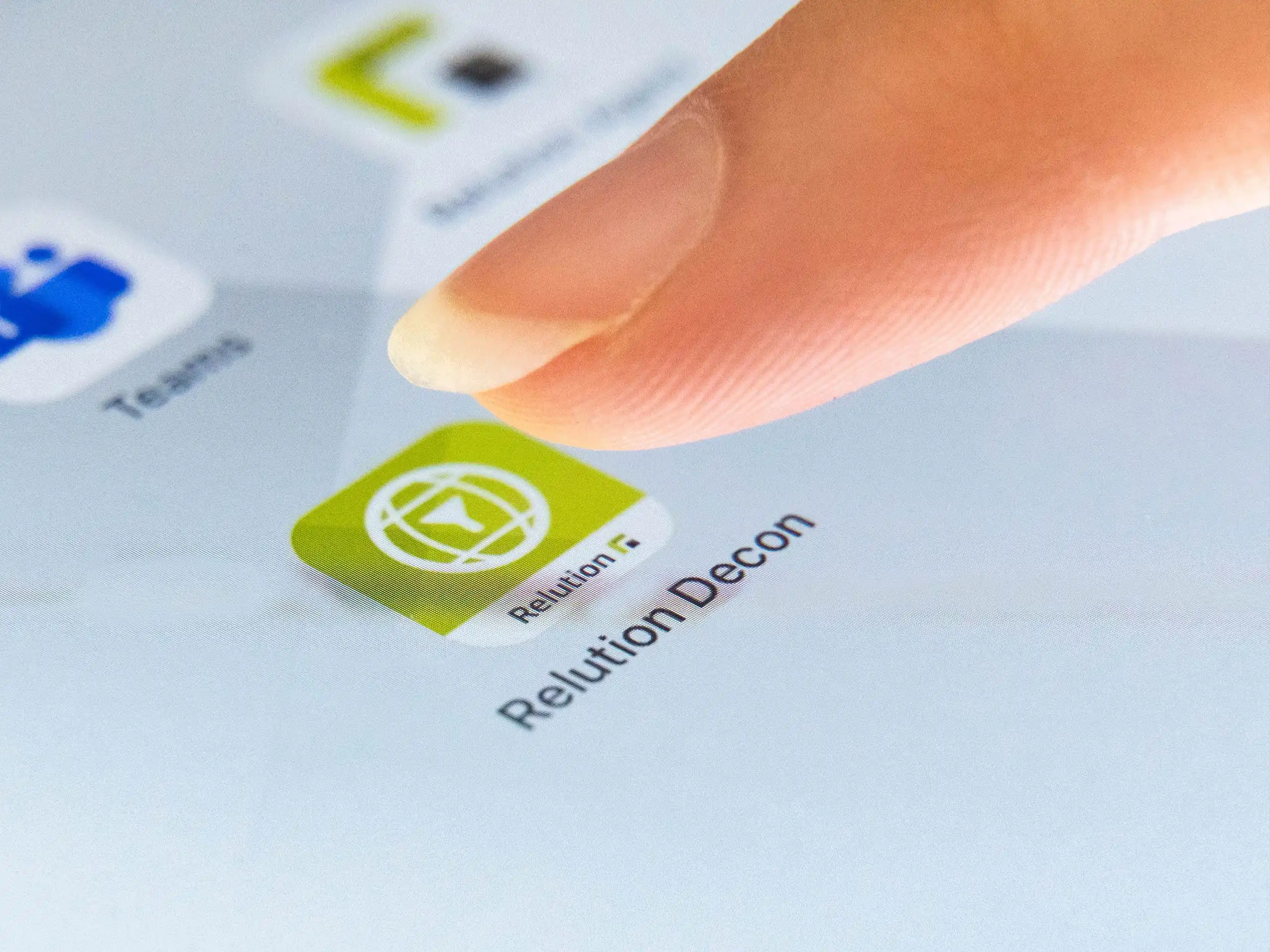Un dito preme sull’icona dell’app Relution Decon visualizzata su uno schermo