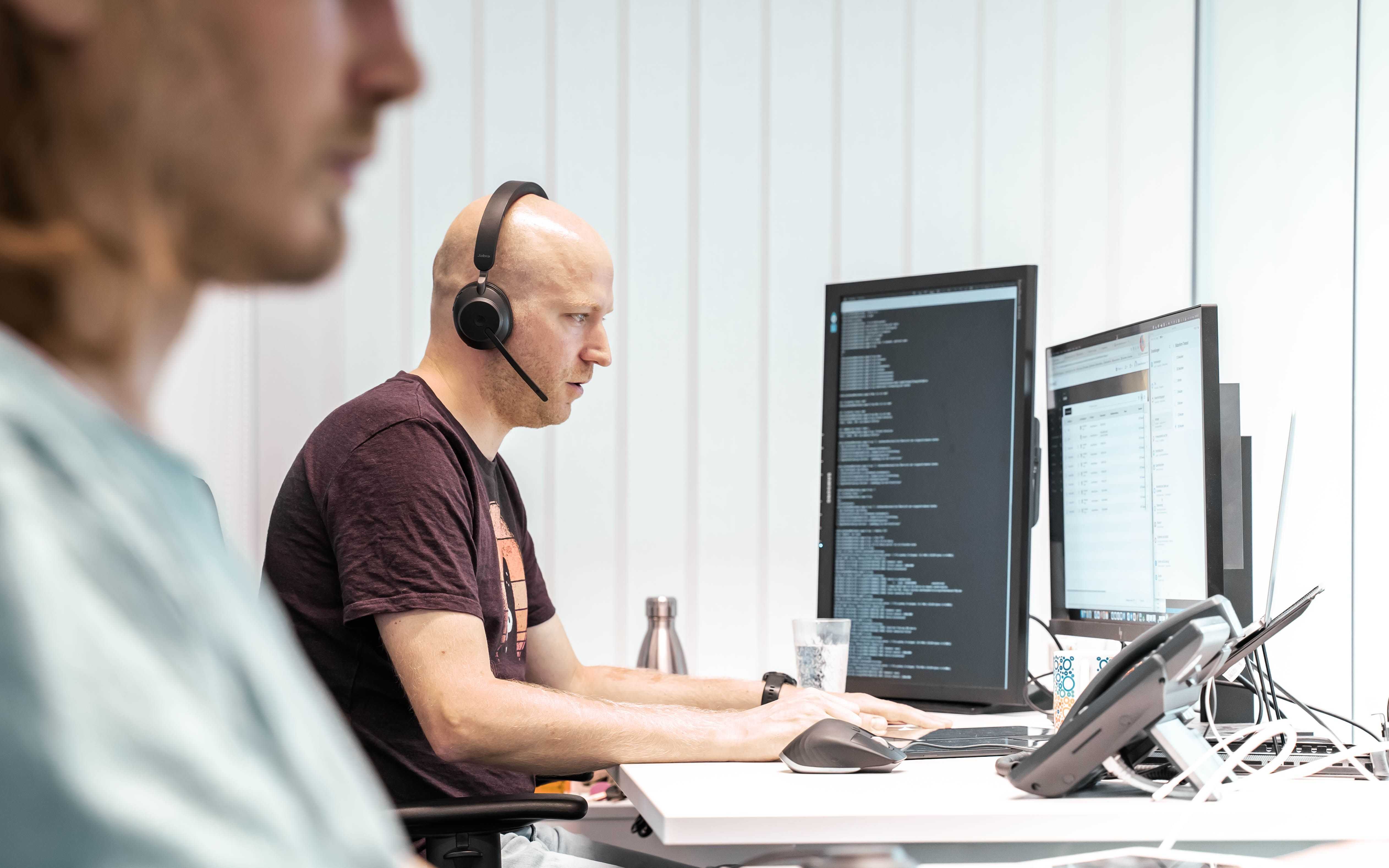 Relution Mitarbeiter Hanno sitzt mit einem Headset vor einem Gerät und schult die Relution Kunden