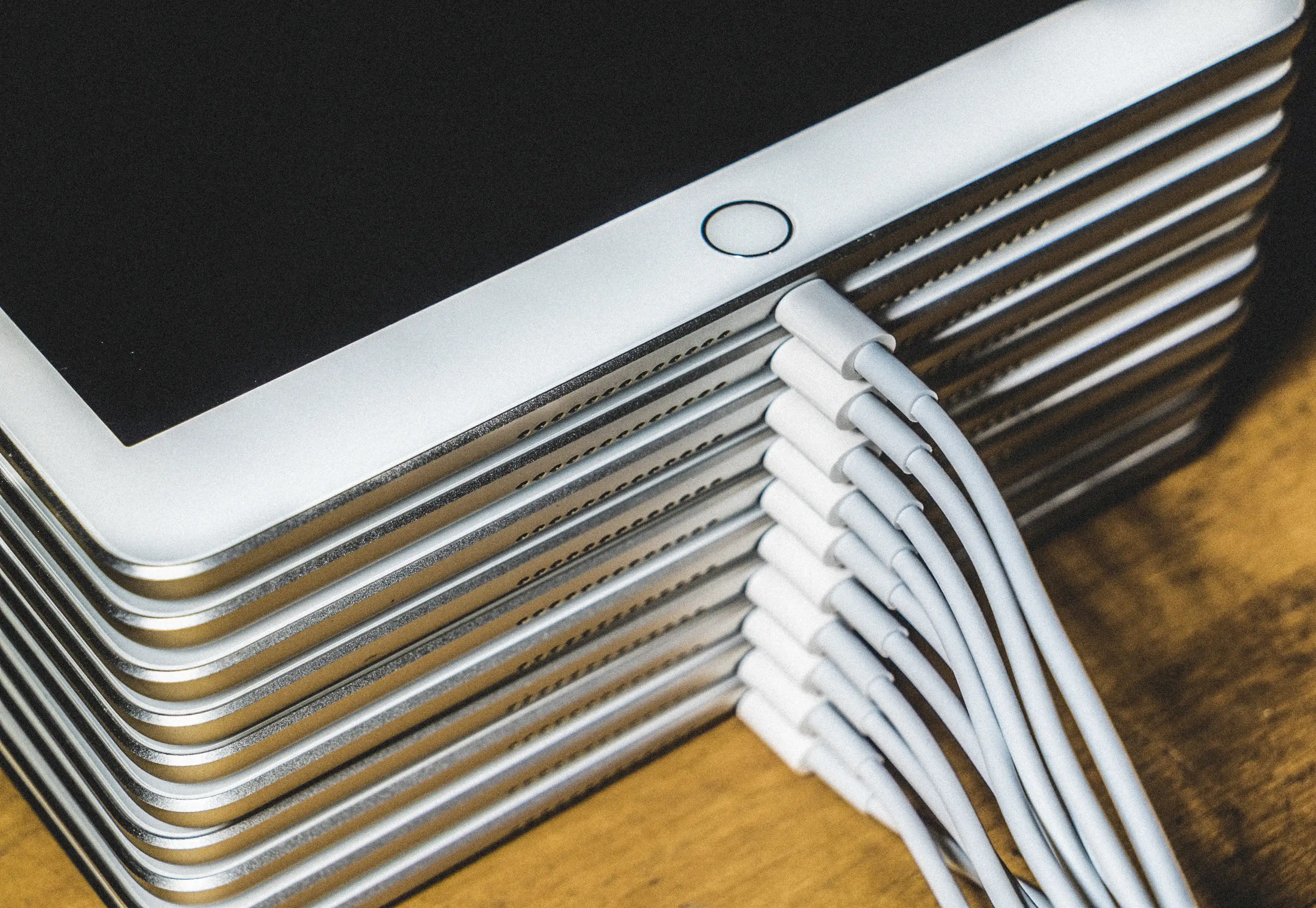 Mehrere iPads liegen gestapelt übereinander, jedes mit einem angeschlossenen Kabel.